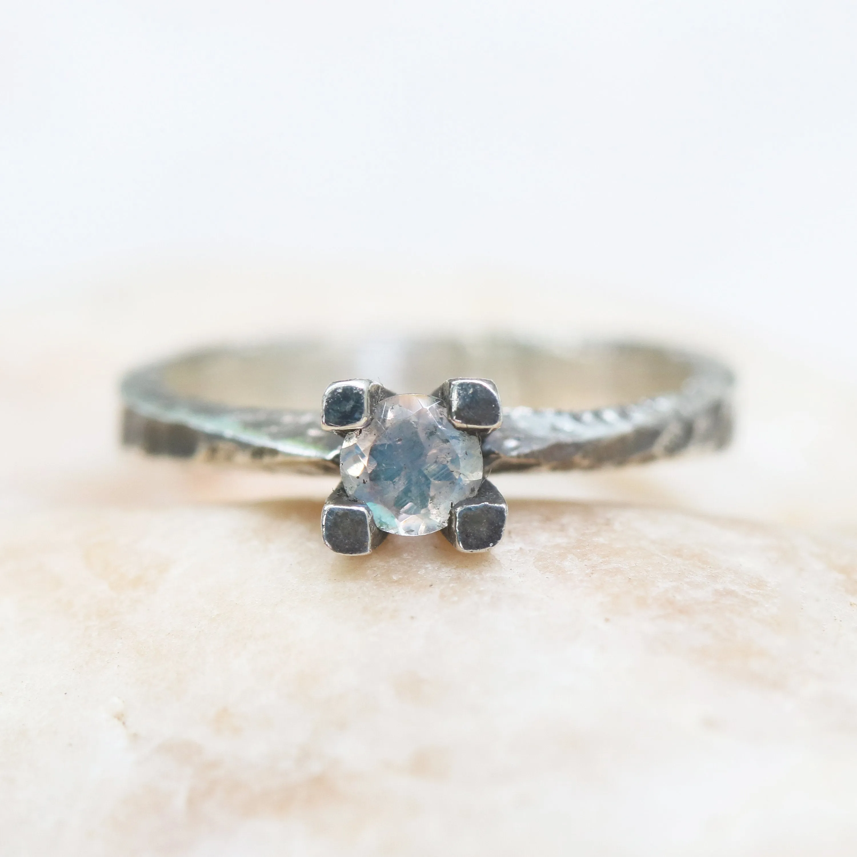 Tiny round faceted moonstone ring in silver prongs setting with sterling silver hard texture oxidized band