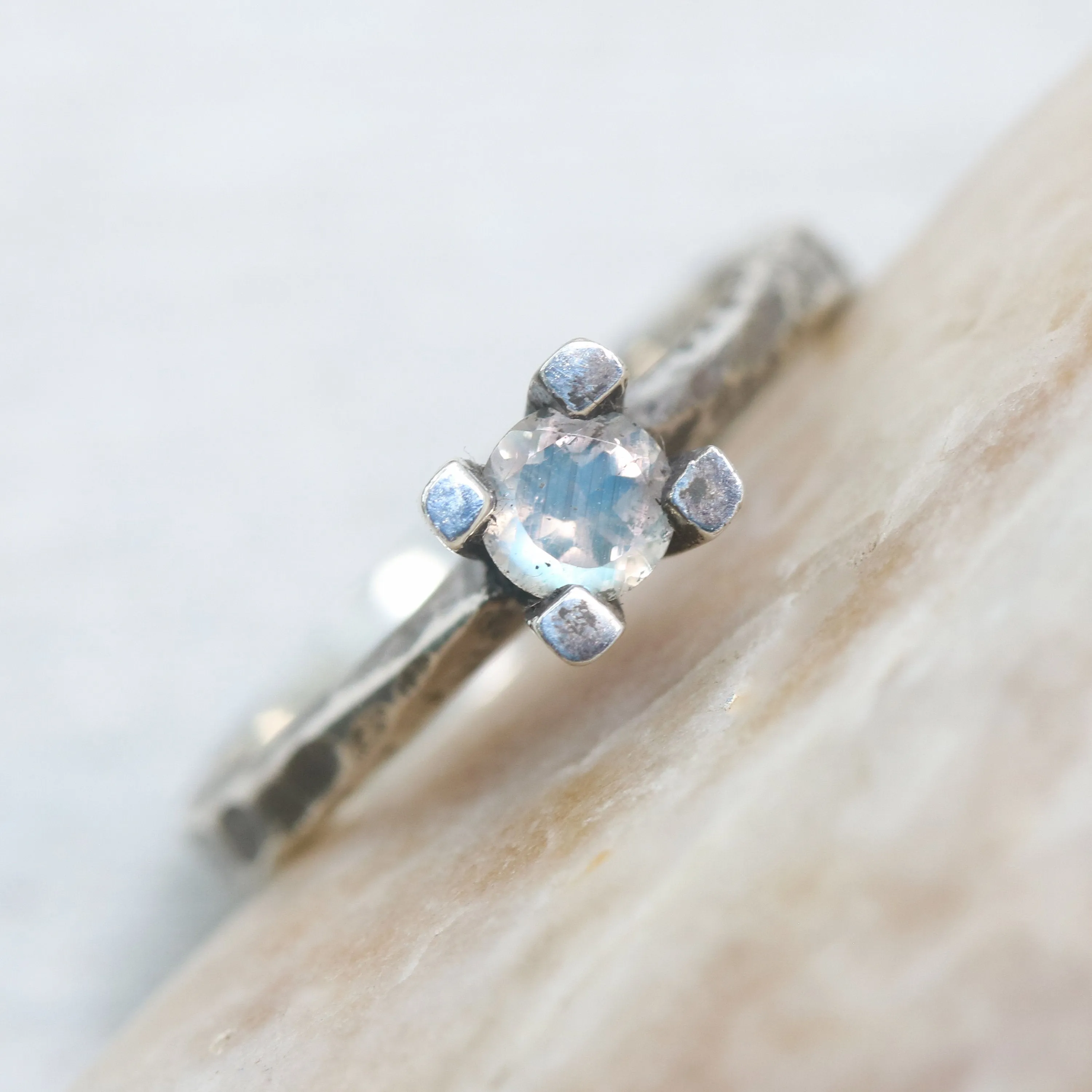 Tiny round faceted moonstone ring in silver prongs setting with sterling silver hard texture oxidized band
