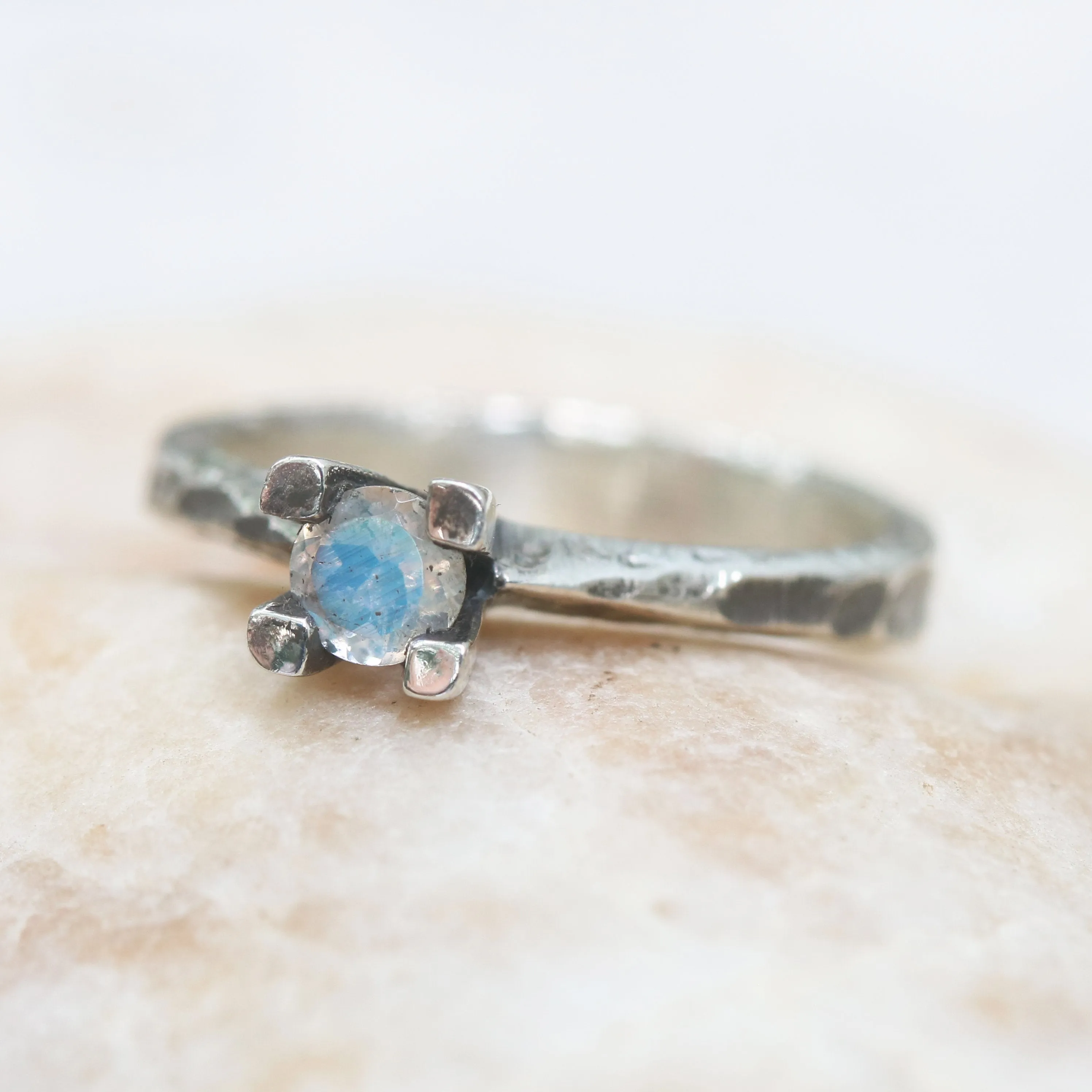 Tiny round faceted moonstone ring in silver prongs setting with sterling silver hard texture oxidized band